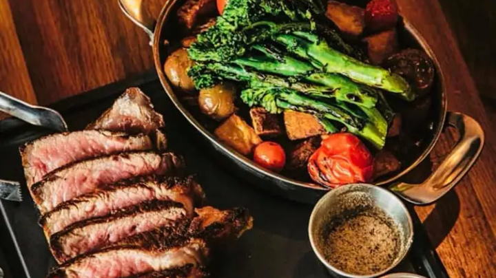 Sliced steak and roasted vegetables with broccoli on a platter.