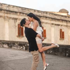 Man lifting woman in embrace near old building.